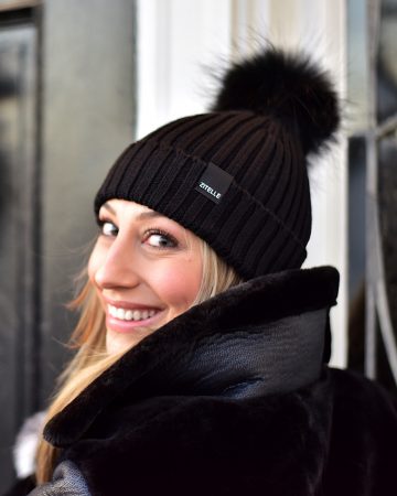 Woman wearing an black ribbed knit beanie with pom